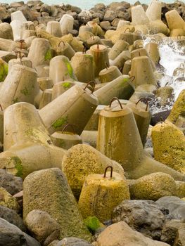 Four armed cast cement tetra-pod bollards scattered randomly so that they interlock forming a protective barrier or seawall against the force of the waves