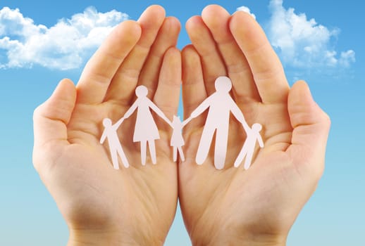 Paper family in hands isolated on blue sky
