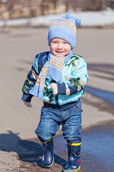 Little boy goes on a pool in rubber boots