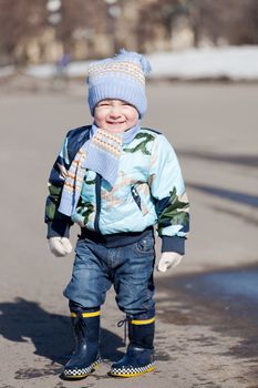 Little boy goes on a pool in rubber boots