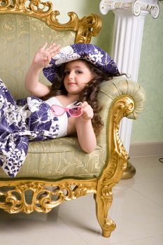 small beauty in sunglasses waving her hand on the armchair
