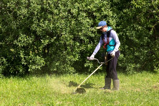 a young man working with a lawn mower trimmer