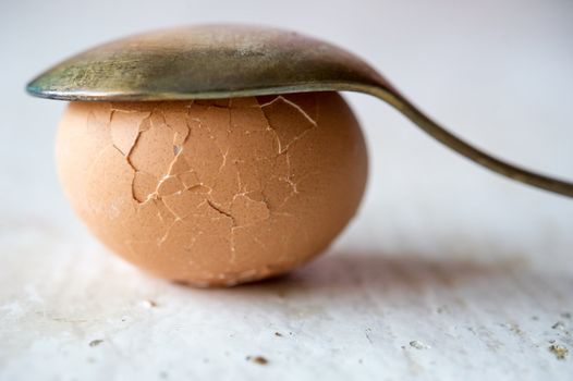 Close up of broken egg with spoon covered on top. Blured background, shallow DOF