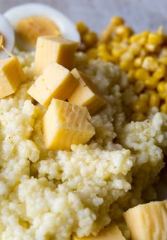 Portion of a barley porridge with eggs, cheese and corn. Close up. Shallow DOF