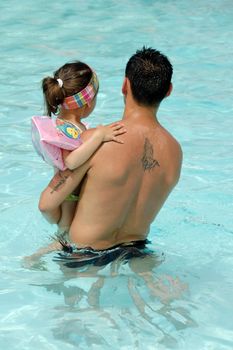 Father and daughter in pool giving eachother a kiss.