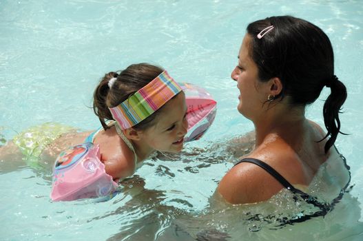 On vacation. Happy woman and child is swimming in pool