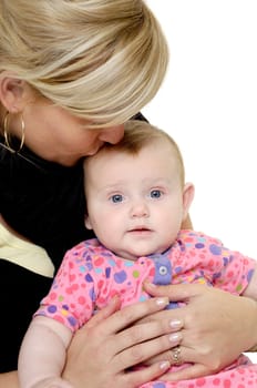 Mother is looking down on her sweet baby while kissing her. Taken on a white background.