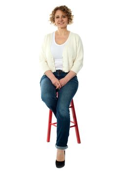 Confident smiling woman sitting on stool and looking at camera