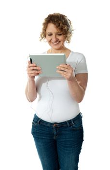 Techy senior woman enjoying music and watching videos on tablet pc