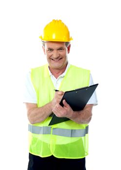 Smiling senior construction engineer writing on documents wearing safty hat and jacket