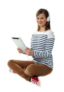 Seated girl enjoying music on portable device smiling in front of camera