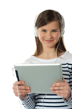Beautiful girl listening to music via wireless tablet wearing headphones and smiling