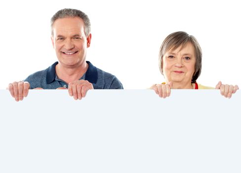 Old age couple holding blank banner ad against white background