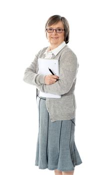 Senior woman holding spiral notepad and pen. Smiling at camera