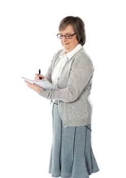 Senior woman writing in spiral notebook isolated over white background