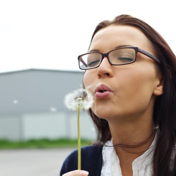 girl blow on dandelion close up 