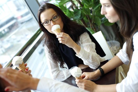 happy smiling women on foreground licking ice cream 