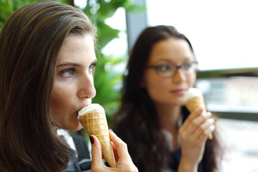 happy smiling women on foreground licking ice cream 