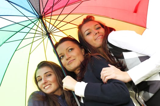 happy smiling girlfriends stay under colourful umbrella  