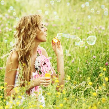  Blonde starts soap bubbles in a green field