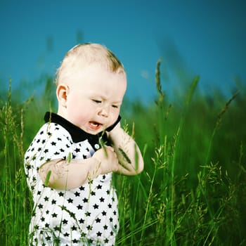 little boy in green grass call by phone