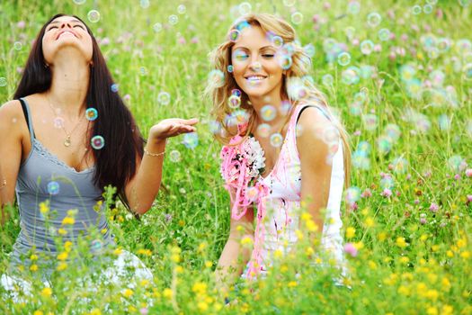girlfriends on green grass field in soap bubbles