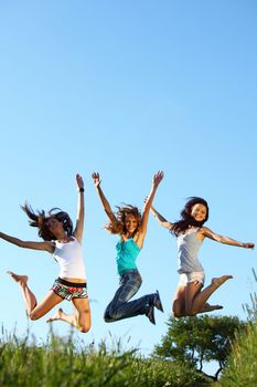 girlfriends jump in green grass field