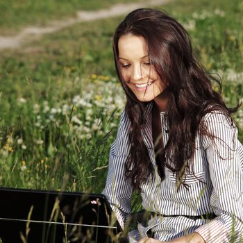 girl with laptop on green grass