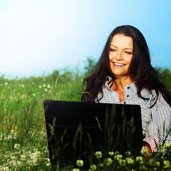 girl with laptop on green grass