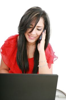 Portrait of a smiling young business woman speaking on mobile phone while using laptop in office