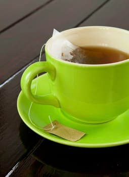 green cup of hot tea on wood background