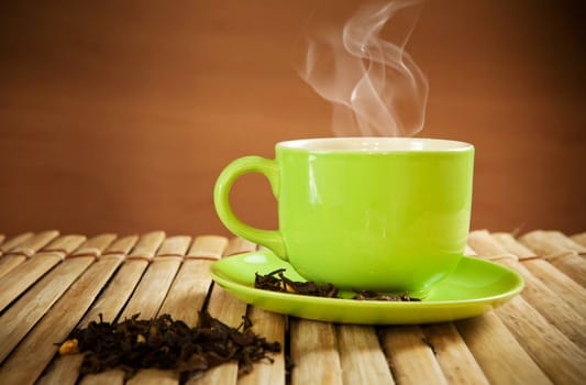 green cup of hot tea on wood background