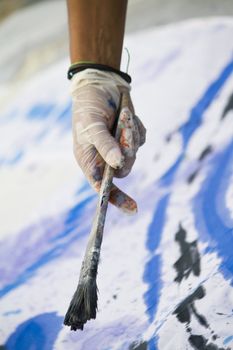 Detail of a hand with a paintbrush painting a colorful cloth.