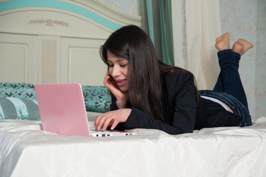 beautiful woman lying on the bed with laptop