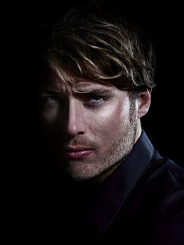 Man - male beauty portrait on black background. Young Caucasian man staring serious close up.