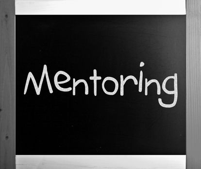 The word "Mentoring" handwritten with white chalk on a blackboard