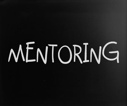 The word "Mentoring" handwritten with white chalk on a blackboard