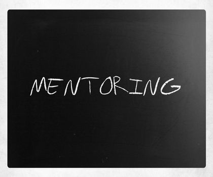 The word "Mentoring" handwritten with white chalk on a blackboard.