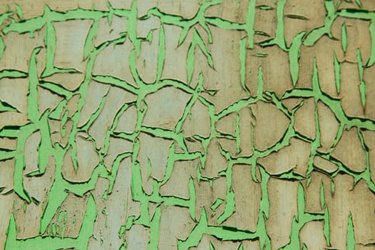 A green painted surface with scratch damageseparating layers of colours.