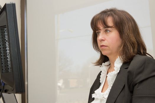 Business woman seated at desk looking at monitor