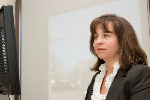 Business woman seated at desk looking at monitor
