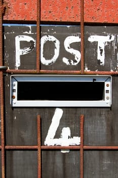 A home made post box with a metal grid and the word 'POST' and number '4' painted in white.