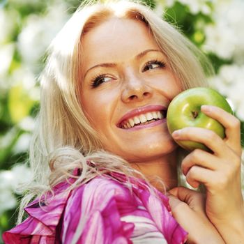 girl with green apple on a background of white flowers