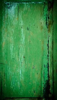 An old wood window panel with cracked green paint and grunge