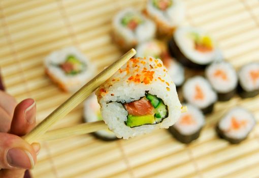 Hand holding sushi. Japanese traditional food. Bamboo napkin in background