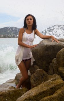 Charming brunette among the rocks by the sea. Thailand. Patong