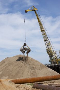 Floating crane scoops soil from the river