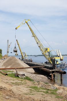 Floating crane scoops soil from the river