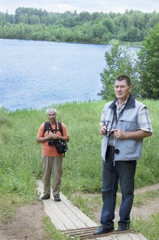 The tourists on the shore of  forest lake