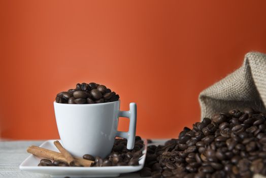 Cup of coffee and beans on an orange vintage background.